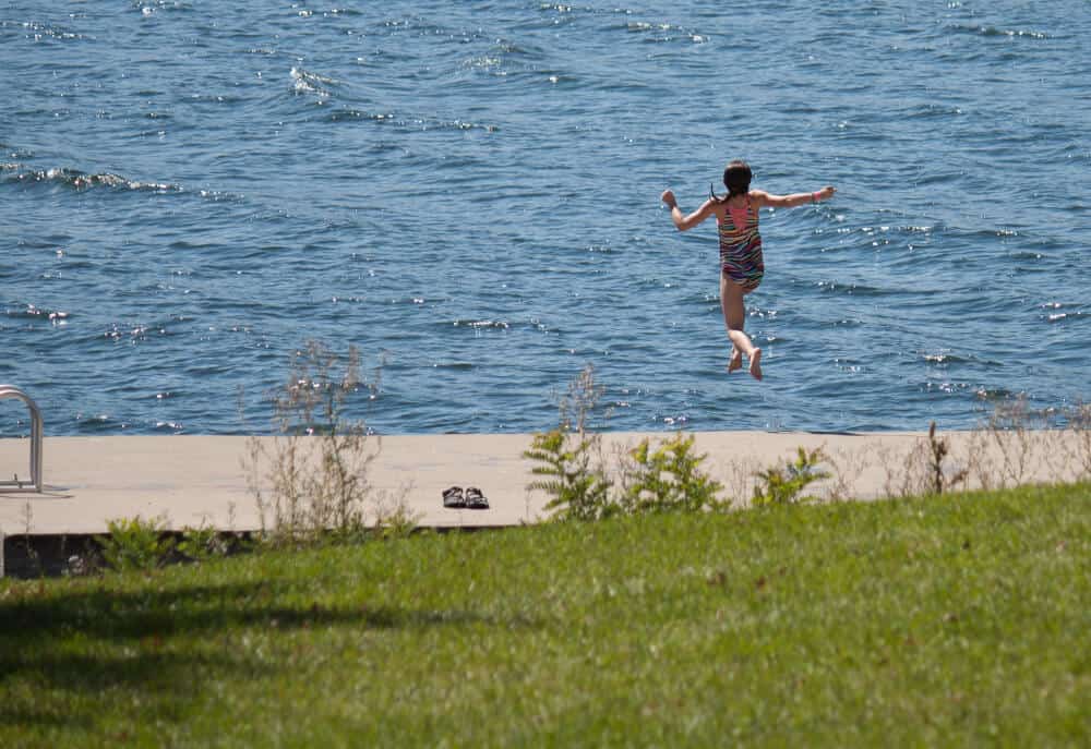 A young girl jumps into the lake in Kingsland Bay State Park in Vermont