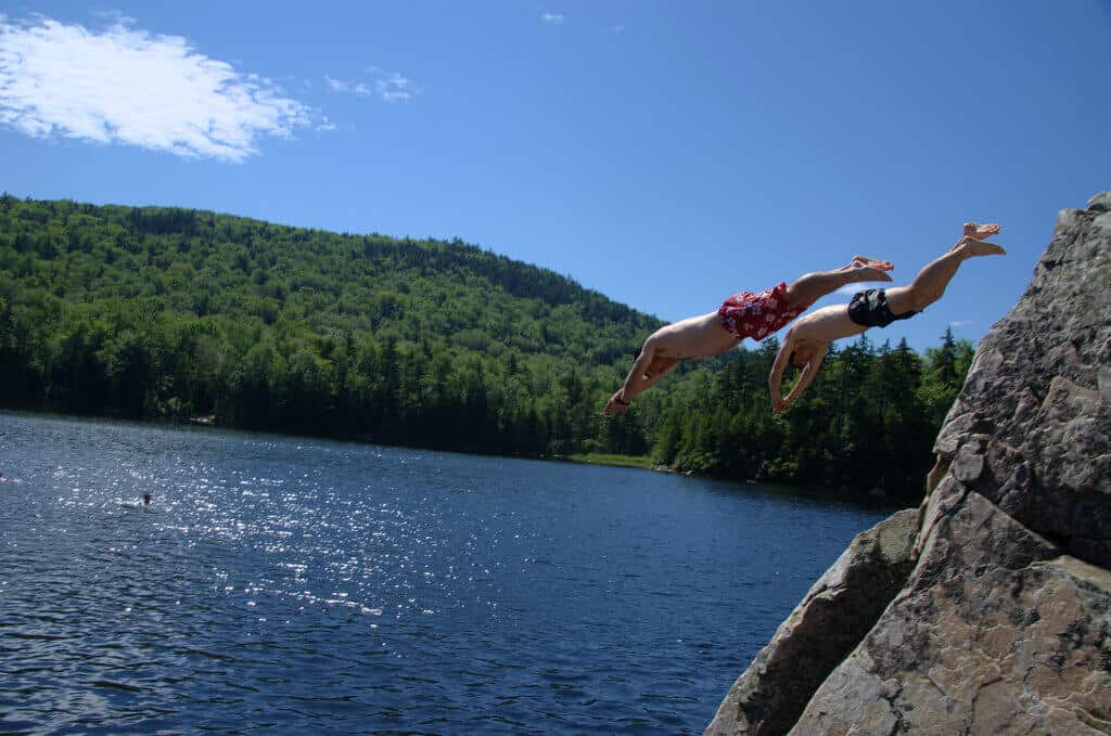 Two boys dive from a cliff into the waters of Little Rock Pond in Vermont