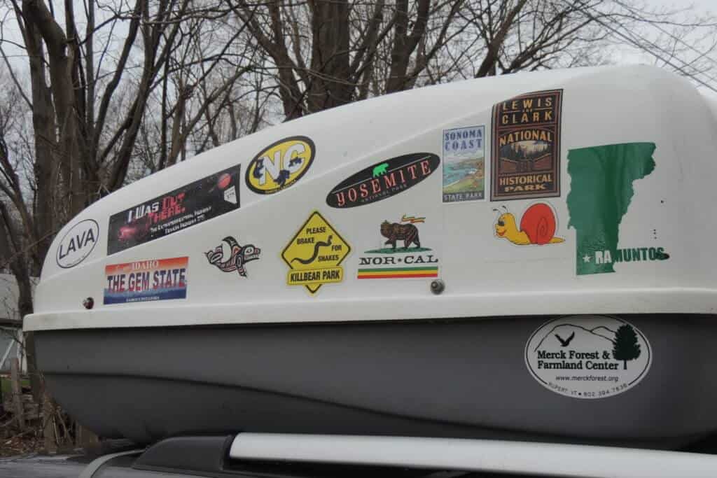 A photo of a white and grey cargo box with stickers all over it.