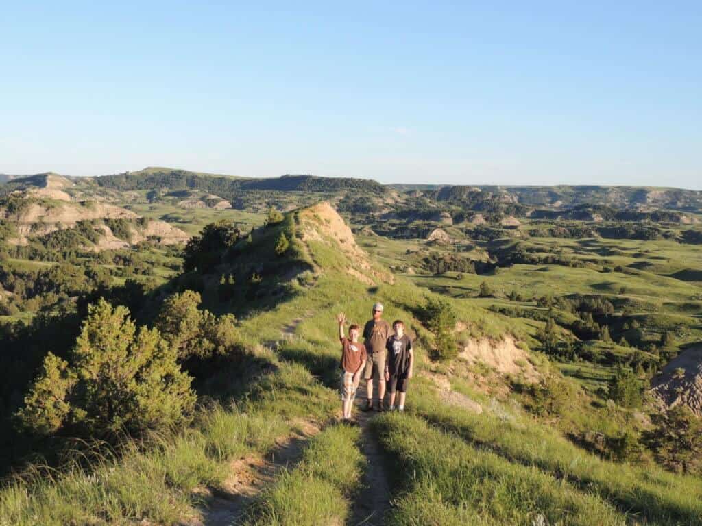A man and two children stand on a hiking trail in Theodore Roosevelt National Park.