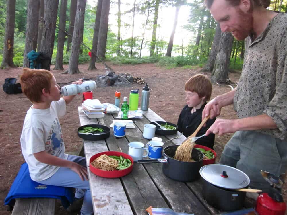 A family enjoys a car camping dinner in the forest. 