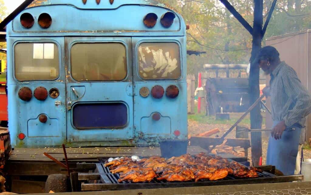 Southern Vermont Getaway in the Fall Curtis of Curtis BBQ, cooking meat on a grill behind a blue school bus.