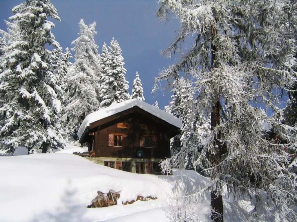 A ski chalet in the mountains, covered with snow. 