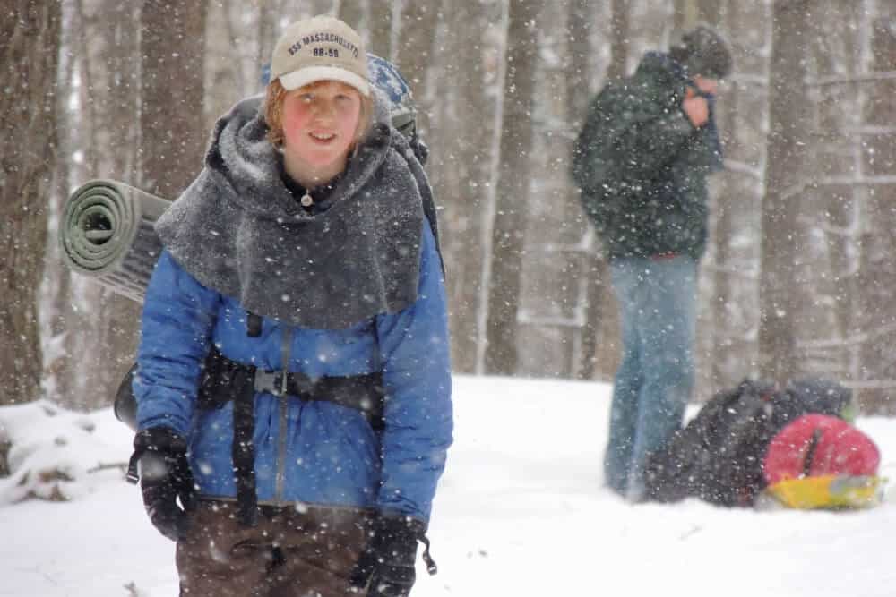 5 Remote Adventures: Cabin Camping in New England 4 A boy hikes through the snow to get to his camping cabin in New England