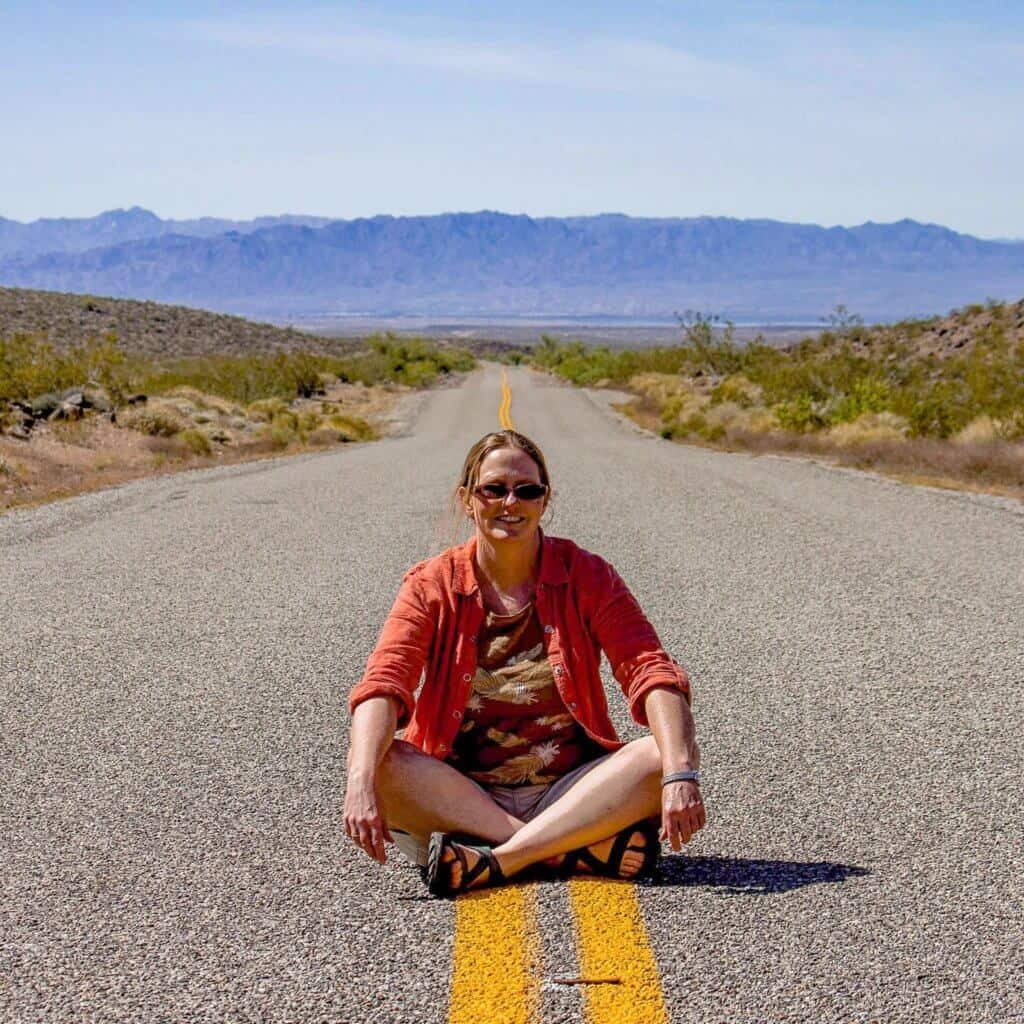 A woman sits in the middle of the road on Route 66 in Arizona.