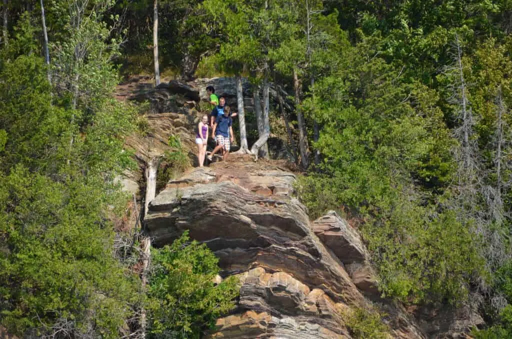 A group of kids stands on a red-rock cliff on the shores of Lake Champlain in Burlington, VT.