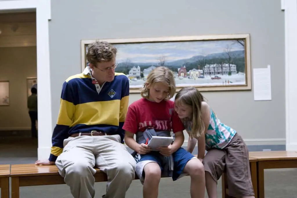 A man sits with two young children at one of the galleries in the Norman Rockwell Museum in Stockbridge, Massachusetts