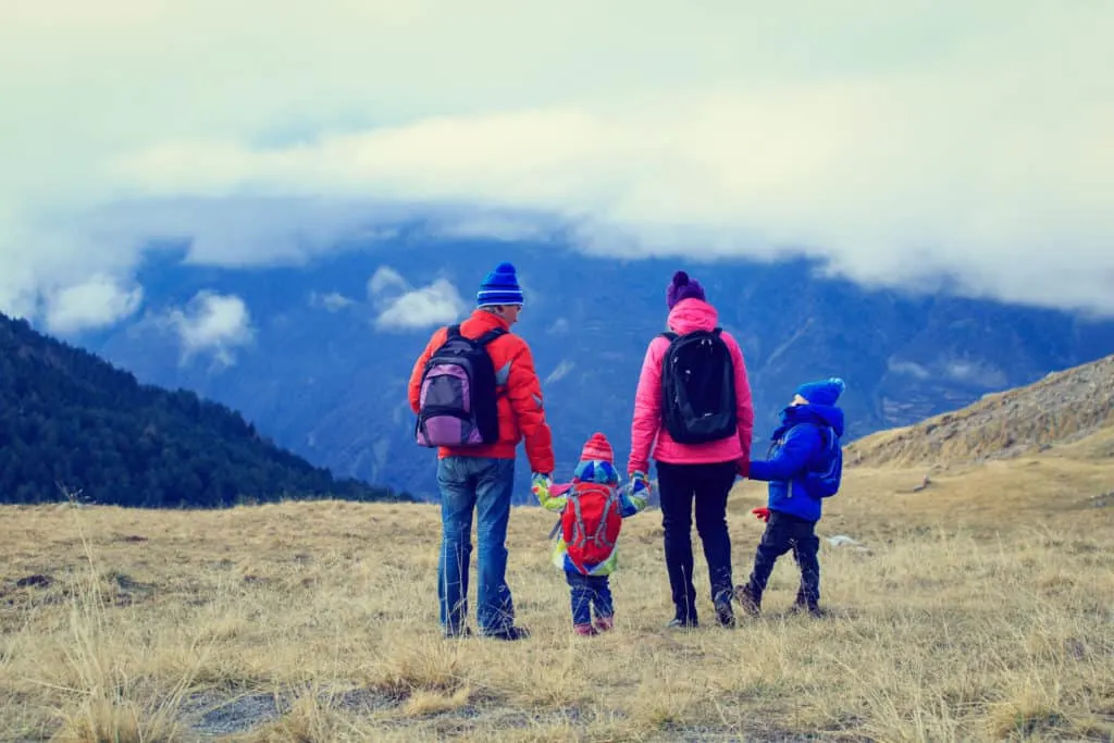 A family is show from behind on a hiking trip in the winter.