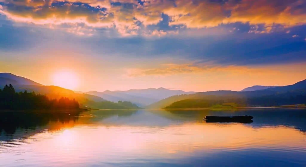 A sun sets over distant mountains and a lake on a spring camping trip.