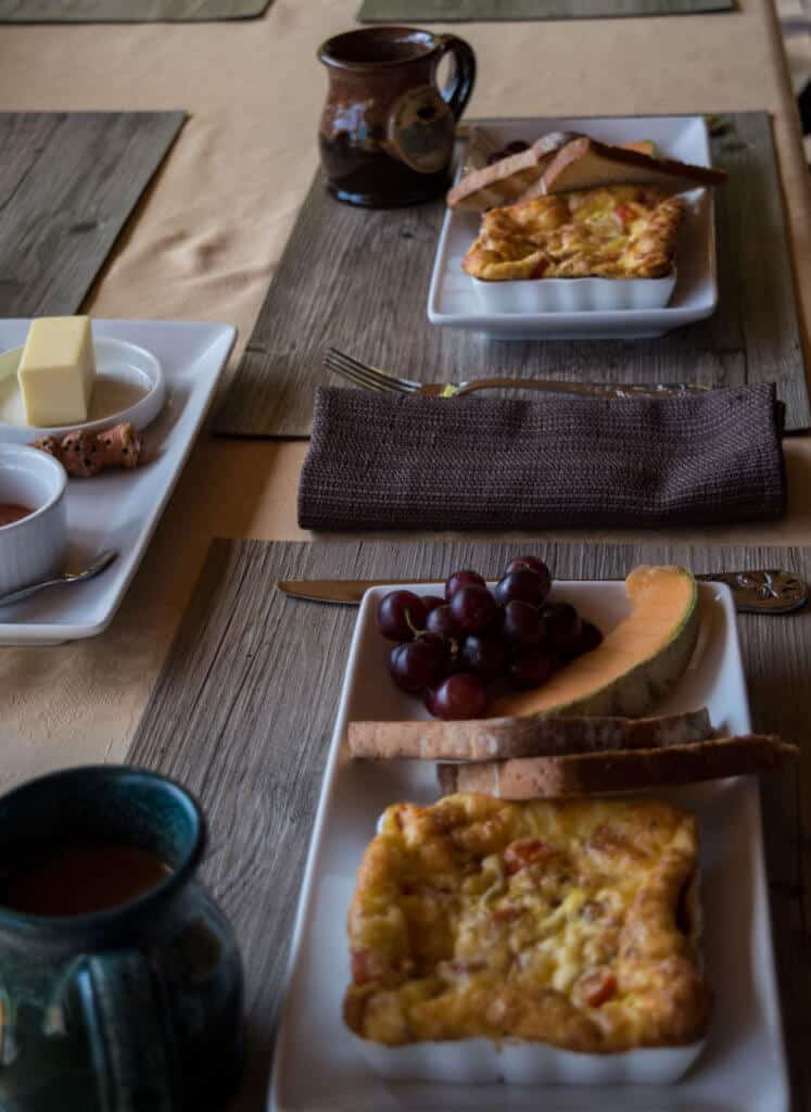 Moose Meadow Lodge and Treehouse in Vermont A table set with breakfast - omelets, grapes, toast, and melons