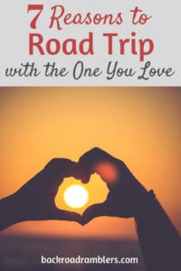Two hands forming a heart around the setting sun. Caption reads: Why a couples road trip will improve your relationship.