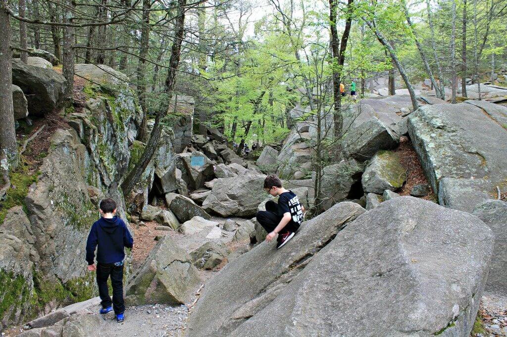 hikers walking and climbing around on boulders in Purgatory Chasm State Reservation