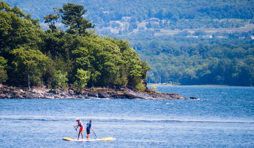 A scene of two stand-up paddleboarders on Lake Champlain in Burton Island State Park