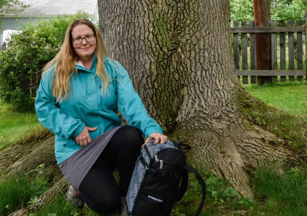 Me wearing a turquoise jacket next to a tree.