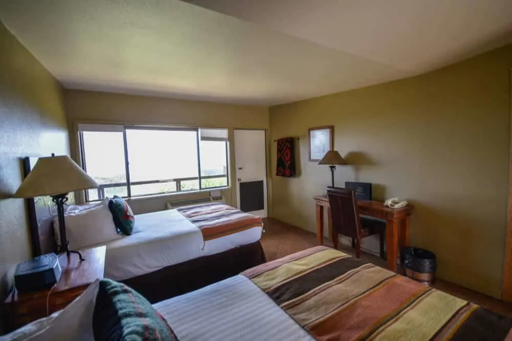 The inside of a hotel room at Far View Ldoge, showing two double beds, a window, and a desk