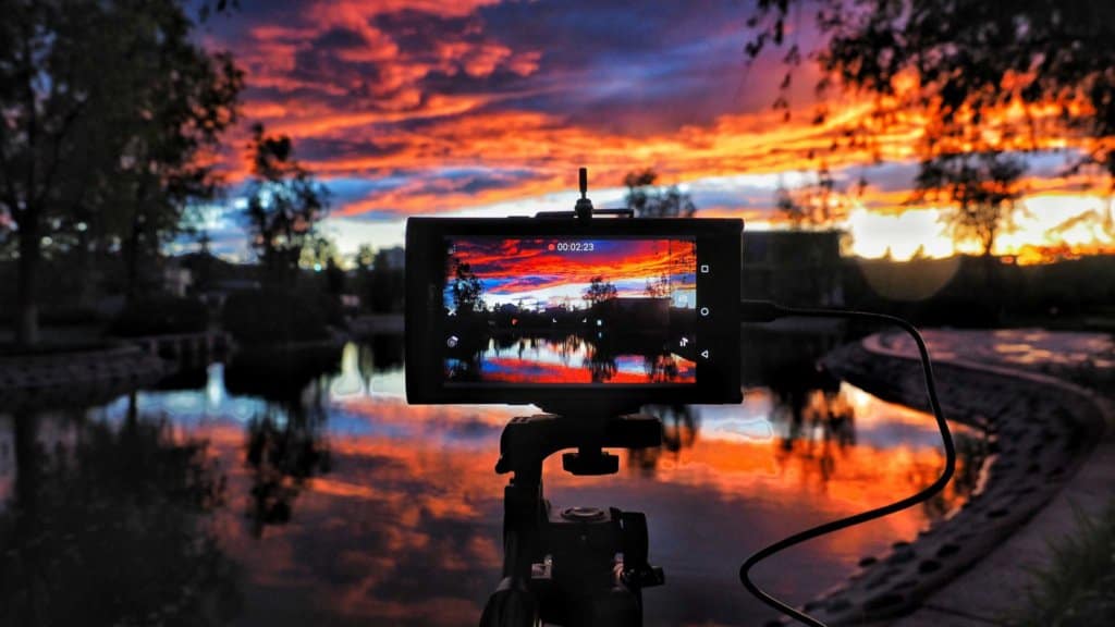 A colorful sunset over a lake with the LCD screen of a DSLR camera in the foreground.
