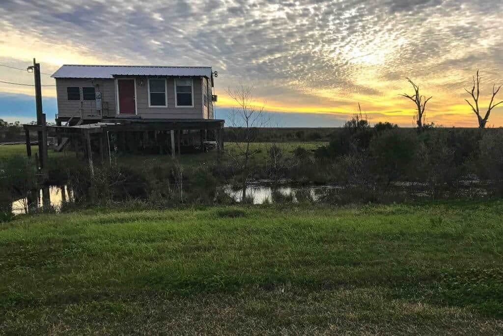 Best Winter Road Trip USA: A Louisiana sunset featuring a house on stilts in the bayou.