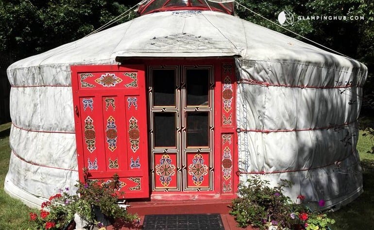 A white yurt with a red door in Saratoga Springs, NY