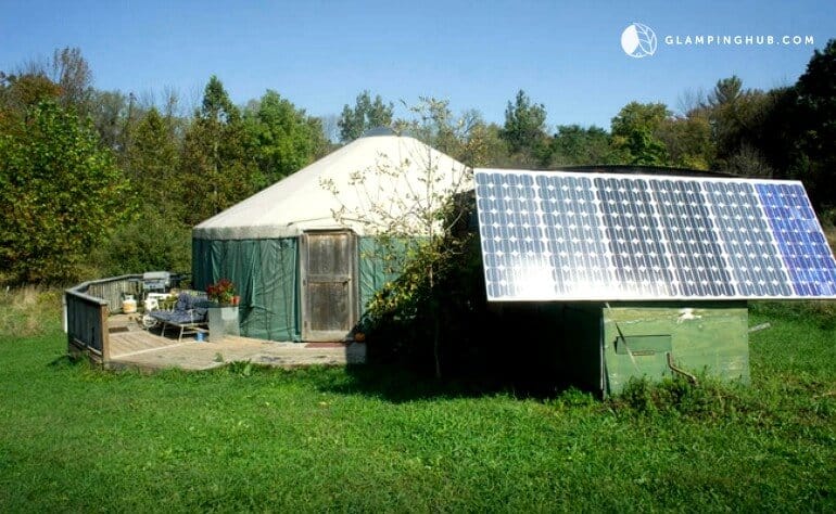 A view of a green yurt in a field next to a solar panel in New York's Hudson Valley