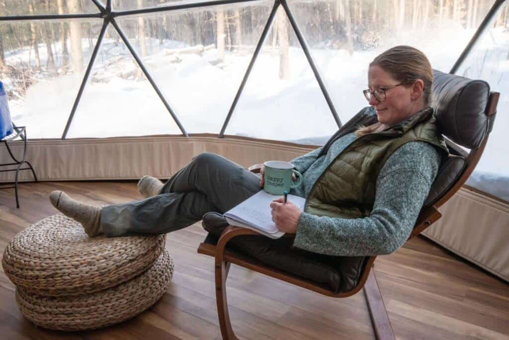 A woman relaxes in a chair while writing in a journal. Putney, VT