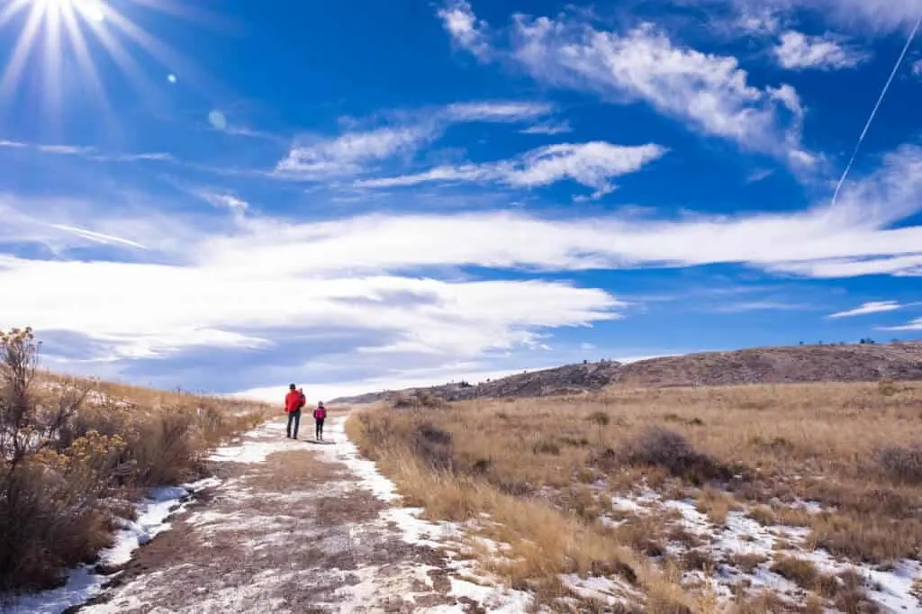 Two people walk on a winter trail in Coyote Ridge Natural Area in Fort Collins, Colorado.