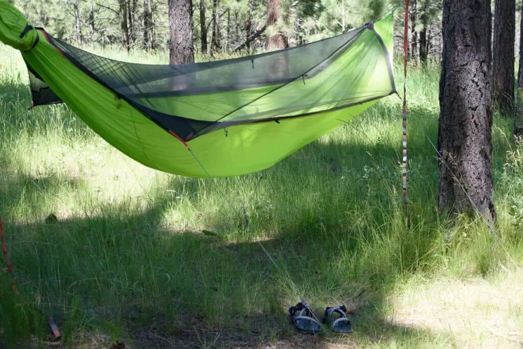 An empty hammock with a pair of sandals beneath it.