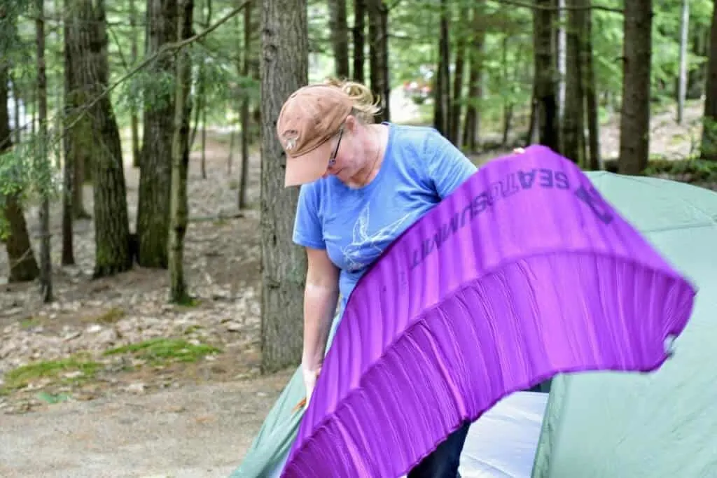 A woman sets up her Sea to Summit sleeping pad next to a tent.