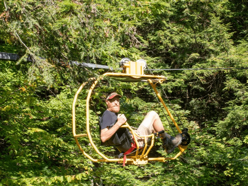 A man cycles through the trees on a recumbent bike at Velo Volant in Au Diable Vert.