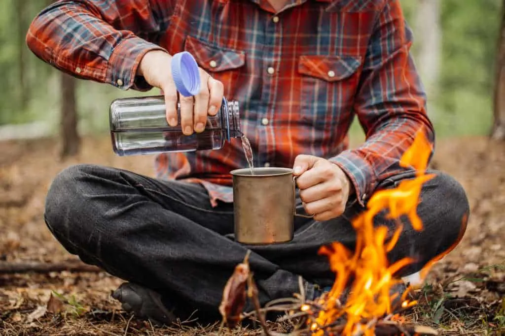 A man pours water into a camping mug.