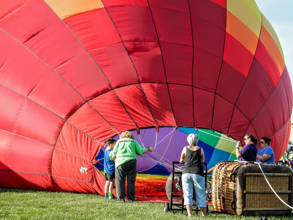 A hot air balloon laying on the ground during the inflation process. 