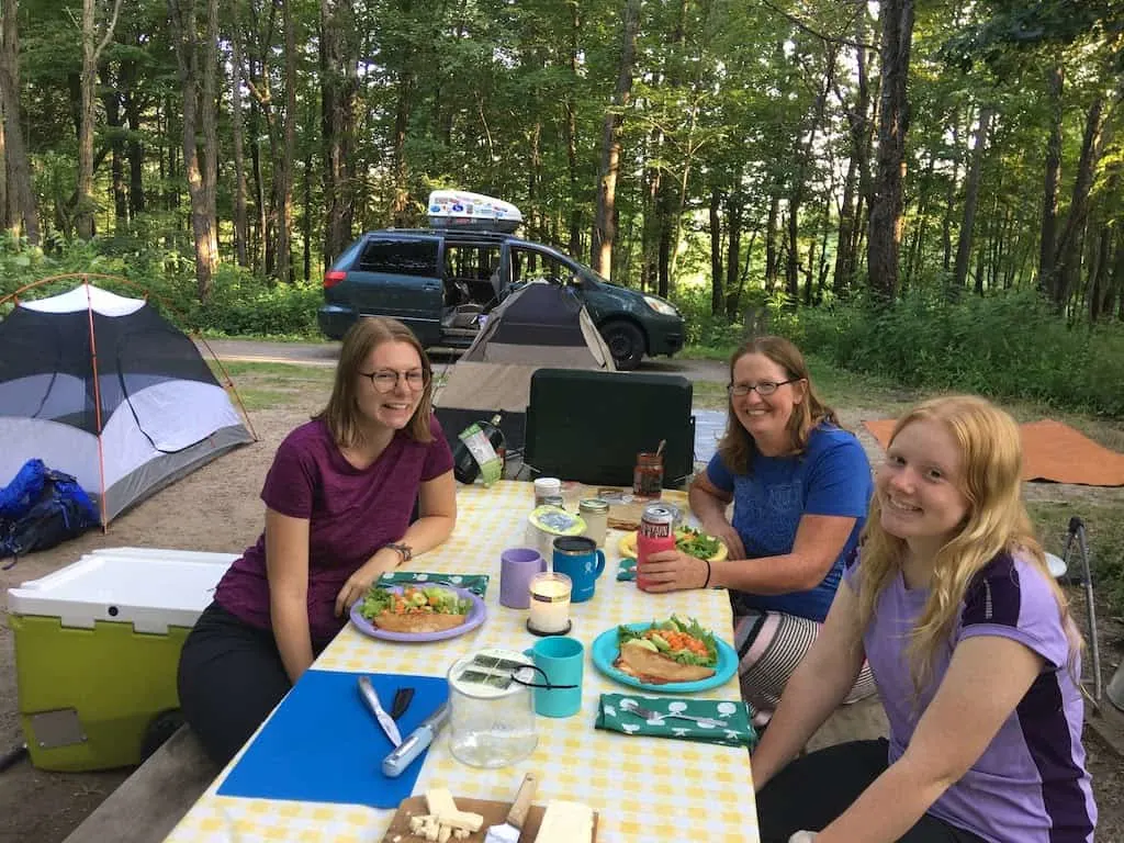 Three women sitting at a picnic table at Dunewood Campground in Indiana Dunes National Park.