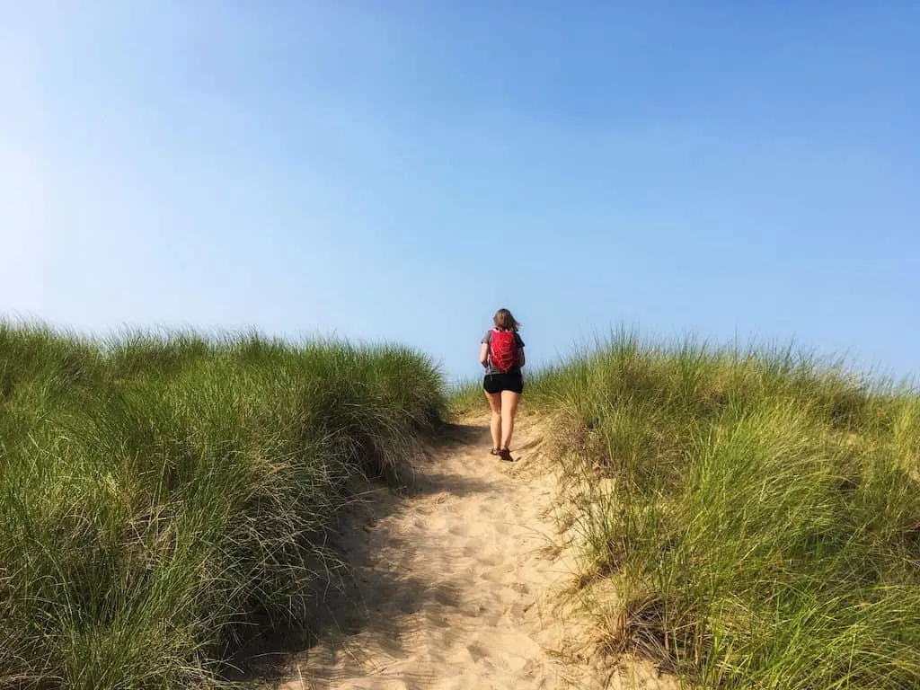 A woman hikes up and over a sand dune in Indiana Dunes National Lakeshore.