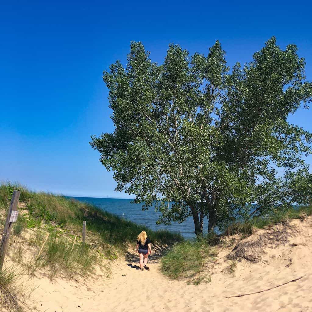 A woman walks down a trail to West Beach at Indiana Dunes National Park.