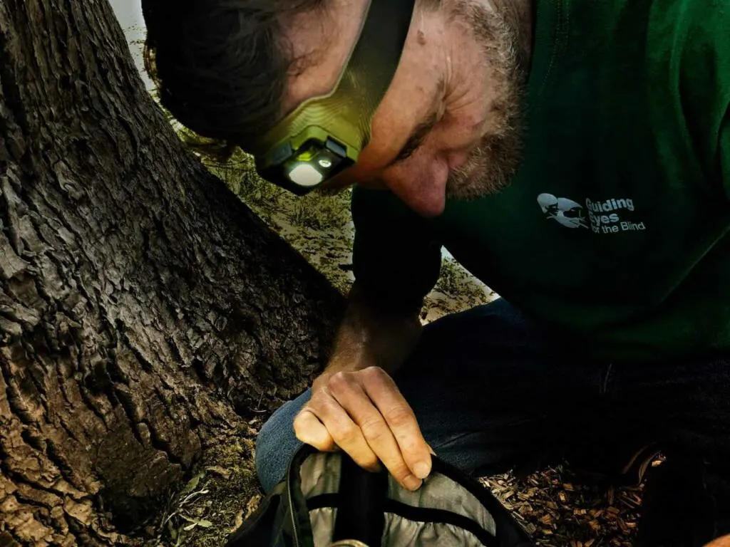 A man wears a Biolite headlamp while search through a backpack. The Biolite hadlamp is one of the best gifts for backpackers.