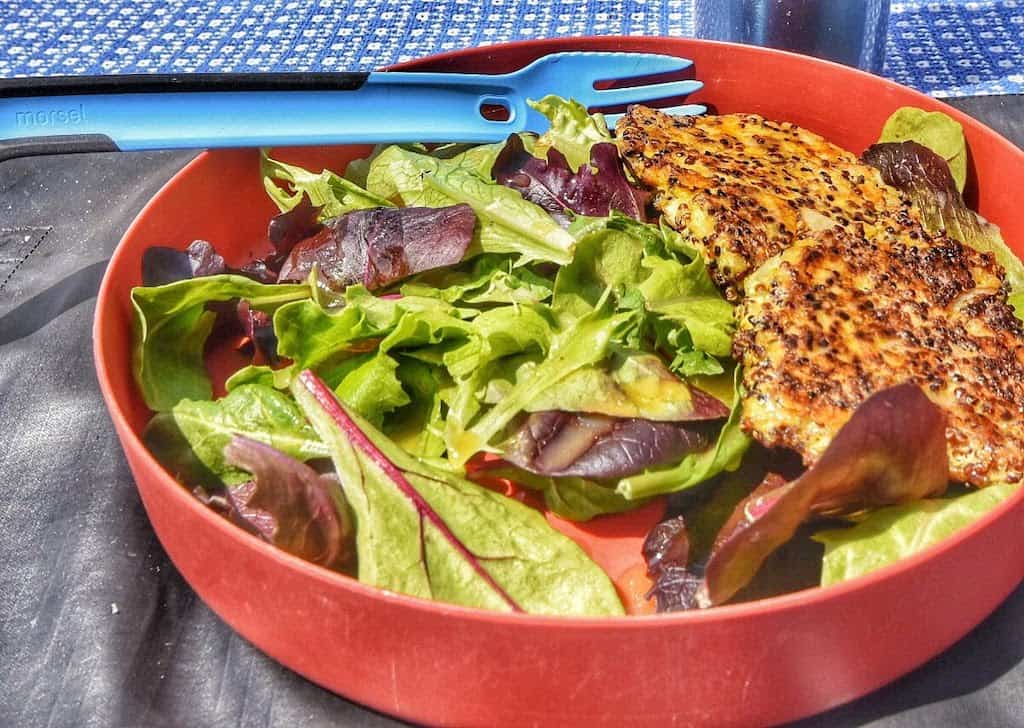 A plate of salad greens and vegetarian quinoa patties for camping