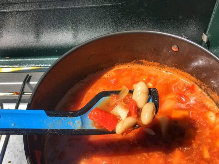 A bowl of white bean tomato soup on a camping stove