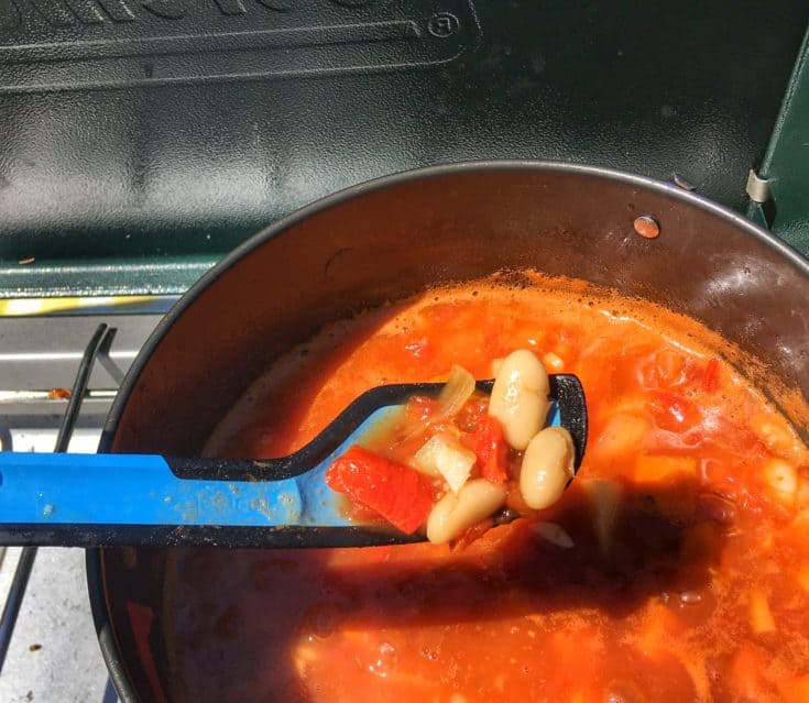 A bowl of white bean tomato soup on a camping stove