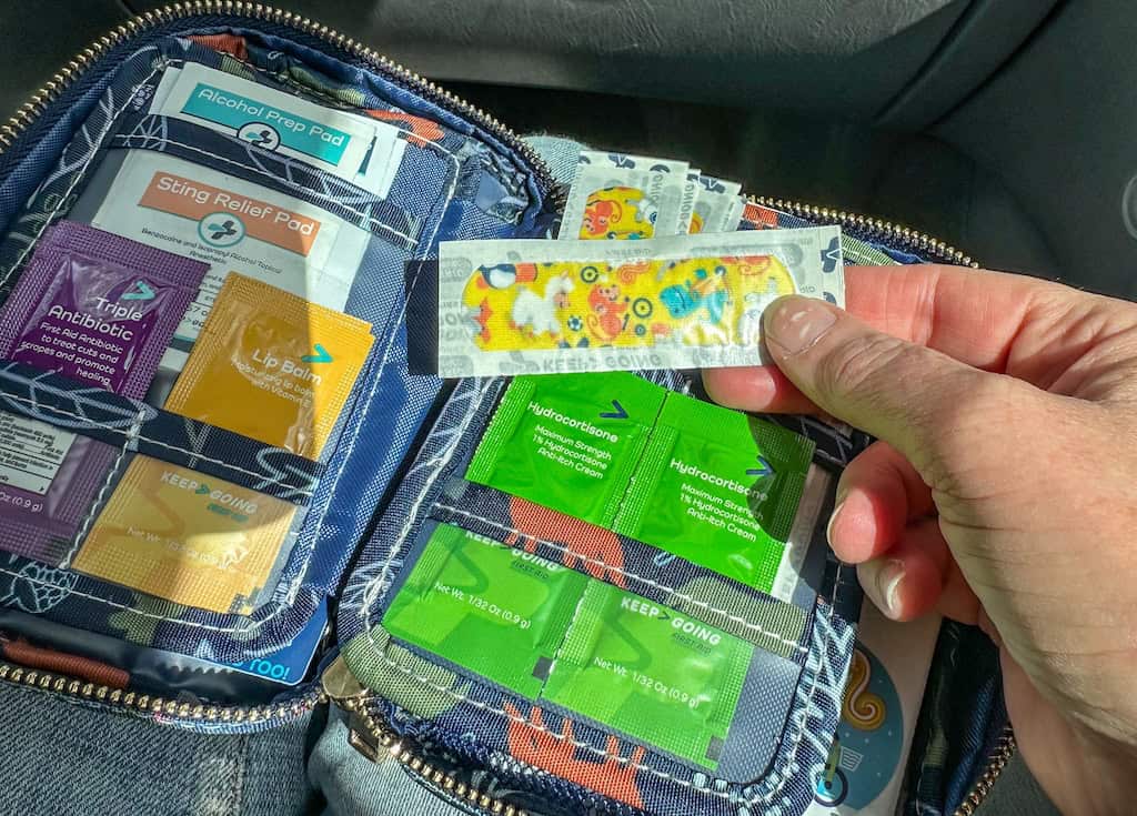 These are the Six Road Trip Essentials We Never Travel Without 2 The interior of a road trip first aid kit with bandages, lip balm, and hydrocortisone.