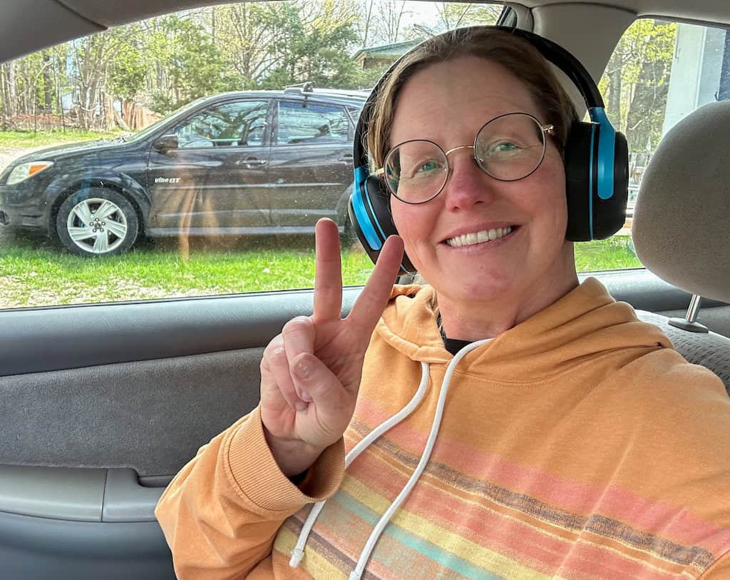 These are the Six Road Trip Essentials We Never Travel Without 4 Tara sitting in a car wearing headphones.