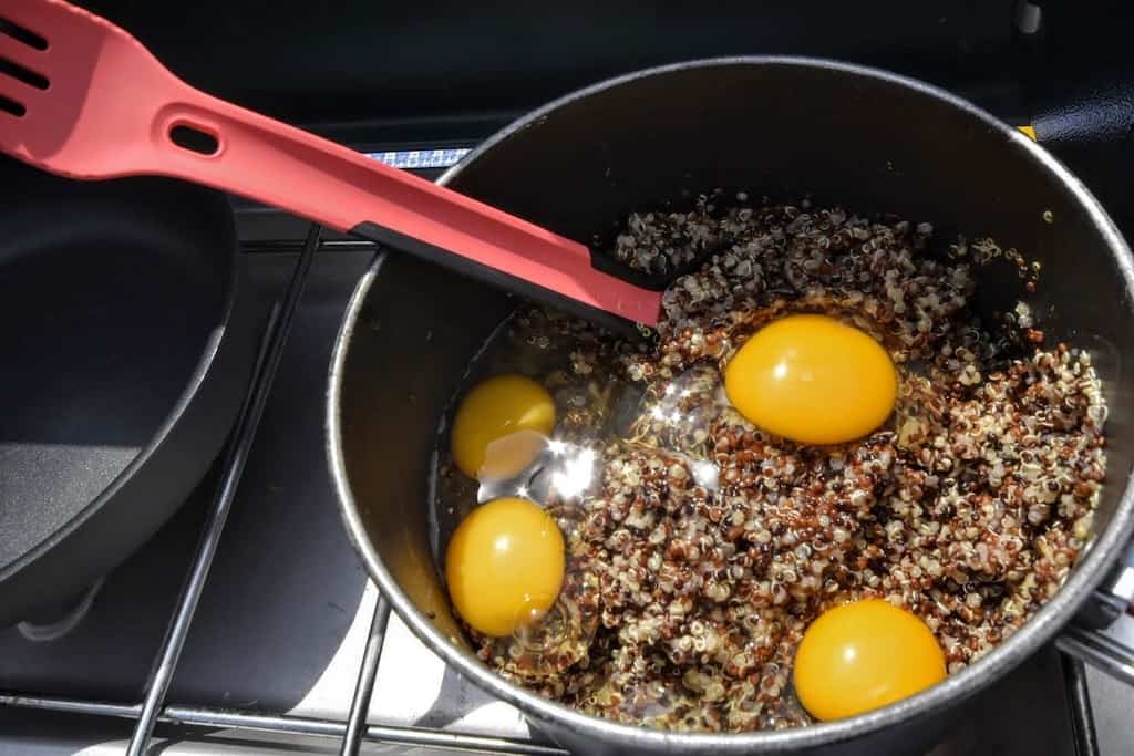 A camping pot with cooked quinoa and eggs in it - the basic ingredients for vegetarian quinoa patties. 