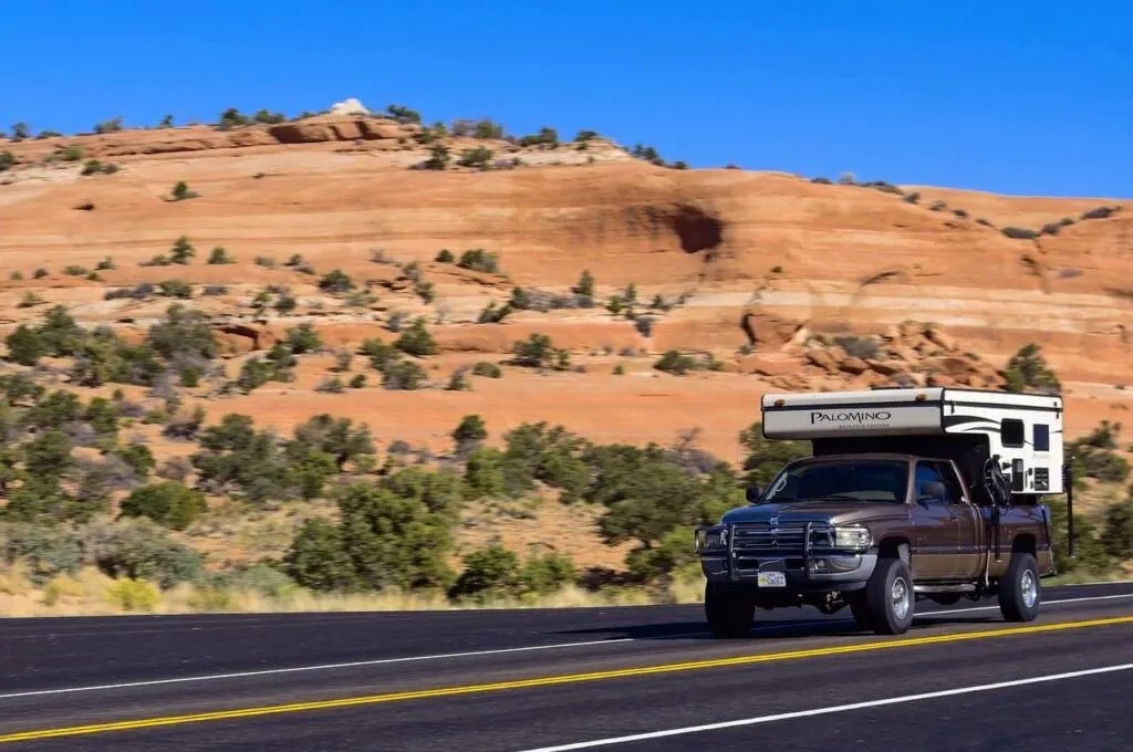 A truck camper driving through the desert