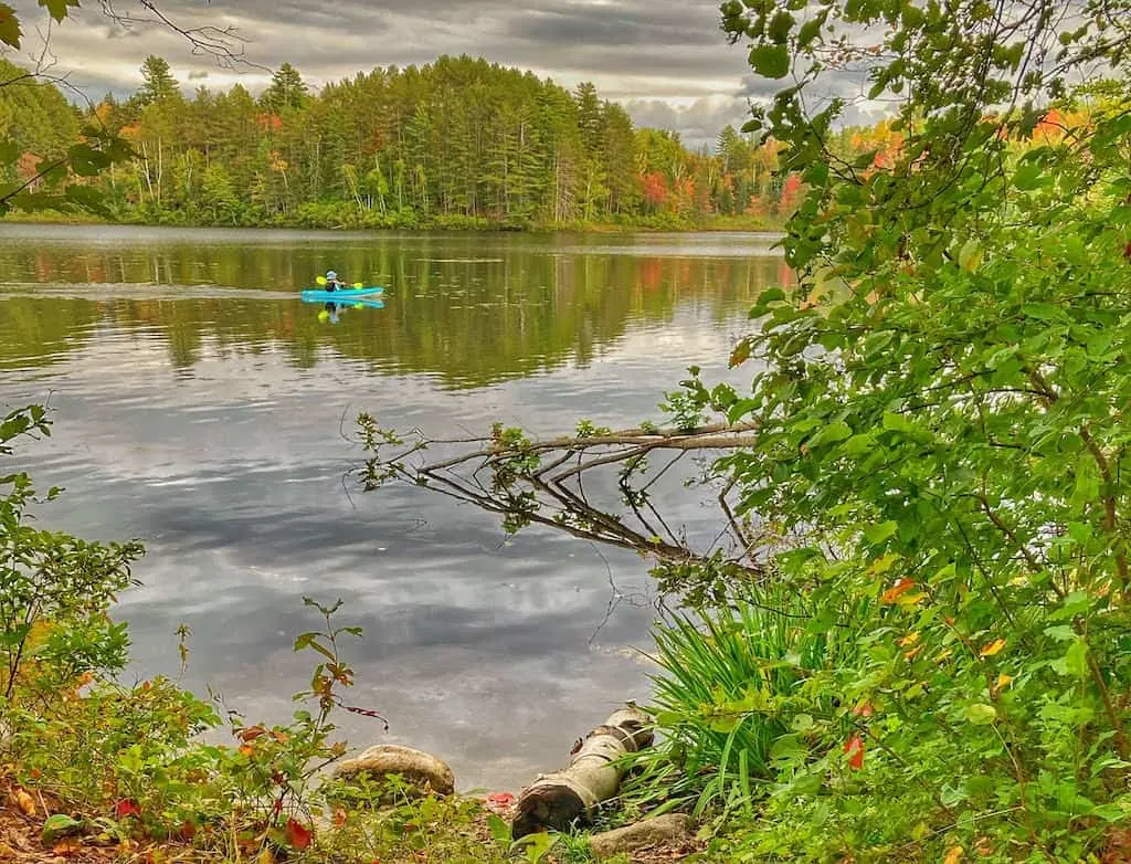 A kayaker glides through the quiet waters of Spectacle Pond in Brighton State Park, Vermont.
