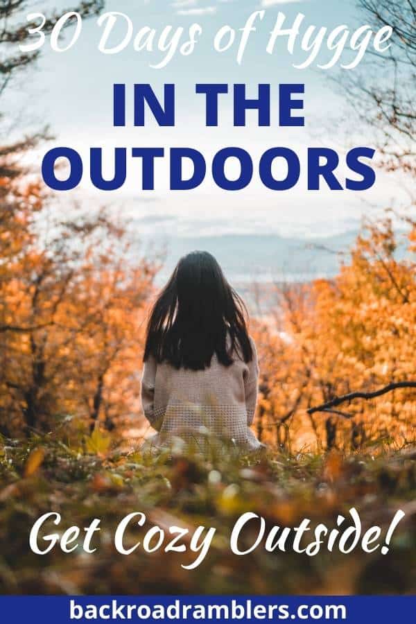 A woman sitting on the hill looking out at distant mountains. Caption reads: 30 Days of Hygge in the outdoors