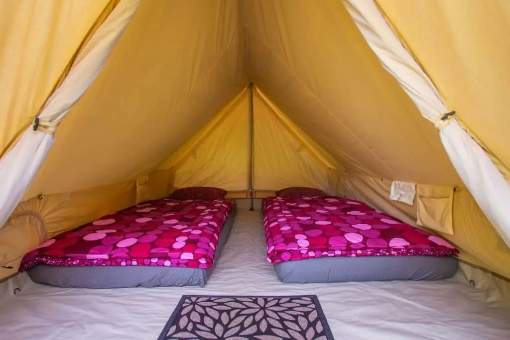 A glamping tent with two air mattresses in it.