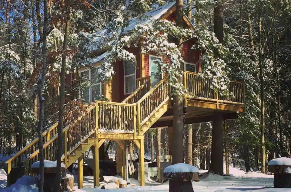 a snow-covered treehouse for rent in New Hampshire.