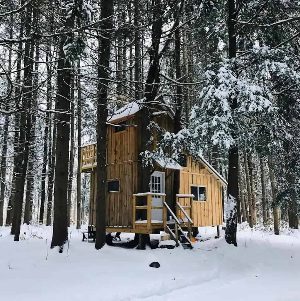 A glamping treehouse in Taberg, NY surrounded by a snowy forest. Photo credit: Airbnb