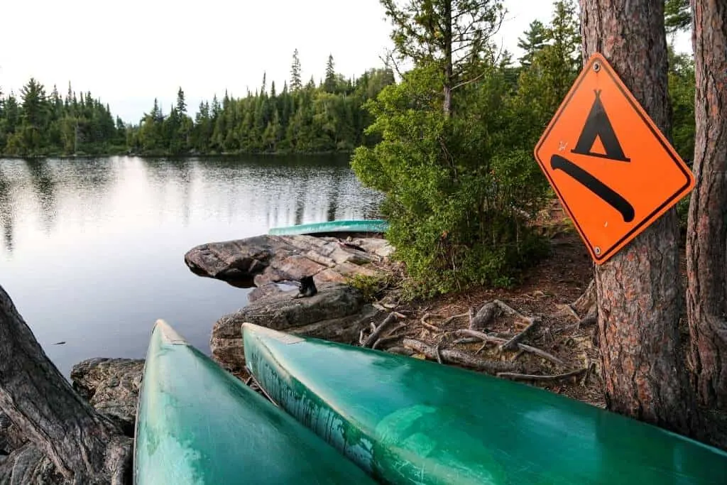 Two canoes rest near the shore of a lake. 