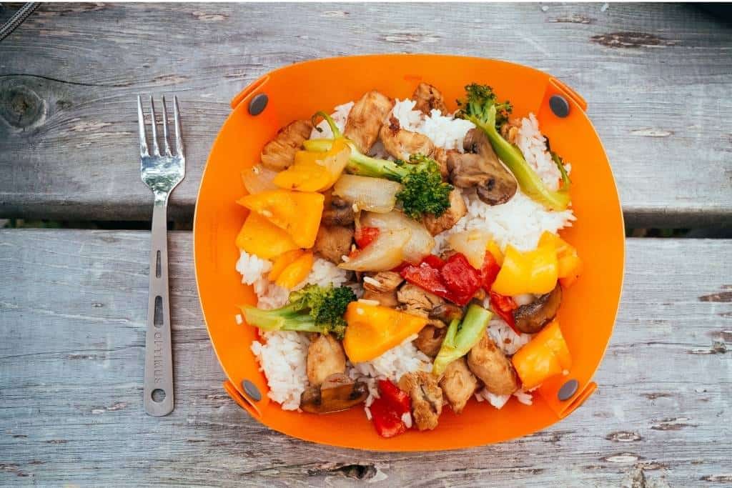 How to Create an Amazing DIY Camping Spice Kit 2 A vegetable stir-fry in an orange camping bowl on a picnic table.