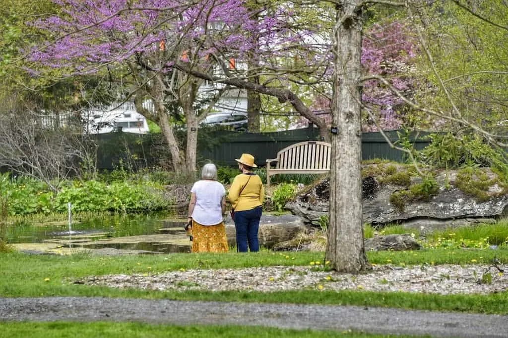 Two woman stand looking at the gardens and pond at the Berkshire Botanical Garden in Stockbridge, MA.