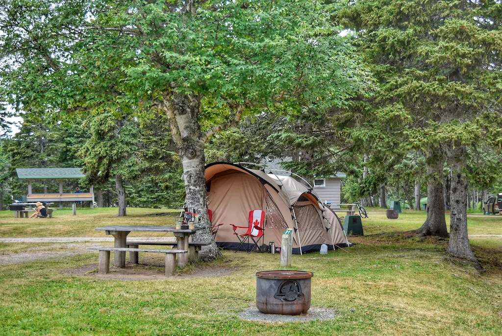 A tent is set up under some trees in Cape Breton Highlands National Park in Nova Scotia.